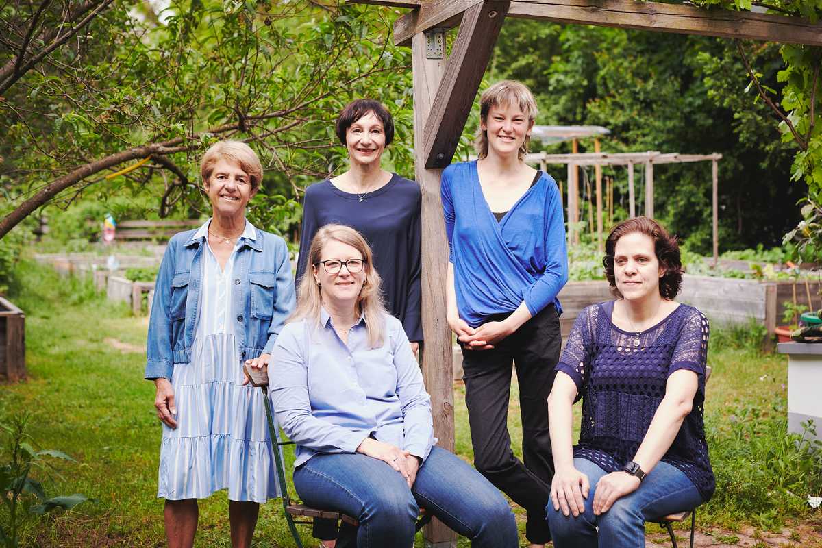 fünf Frauen stehen oder sitzen in einem Garten