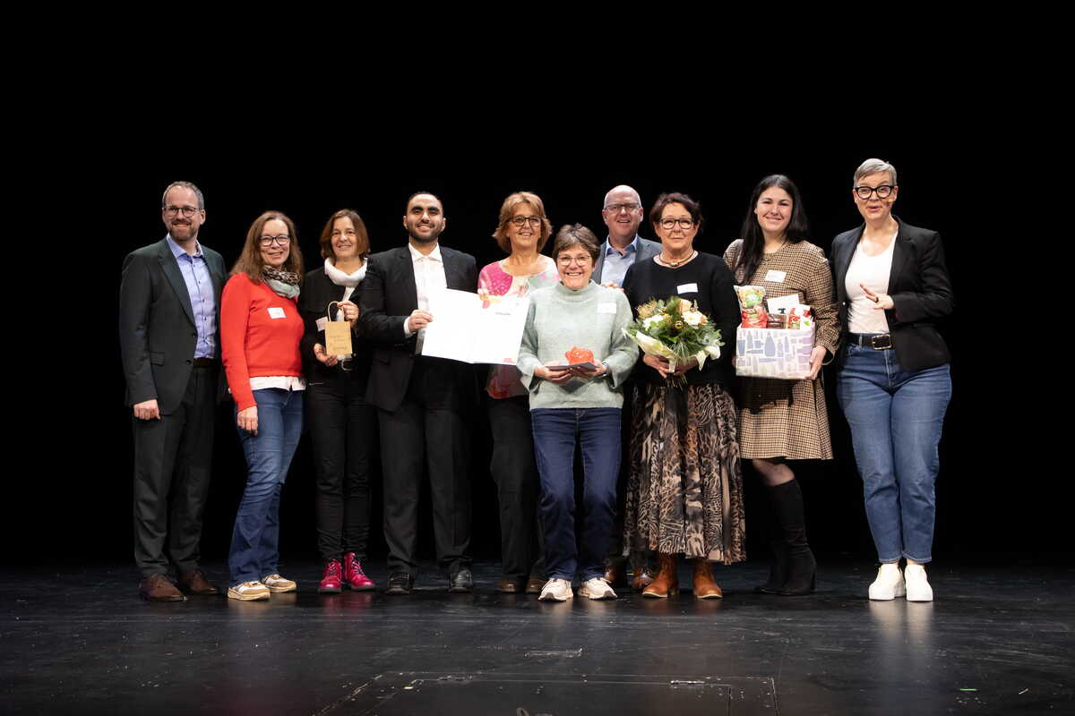 Menschen mit Urkunde auf einer Bühne