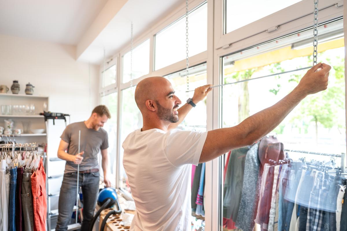 zwei Männer hängen Stangen im Schaufenster auf