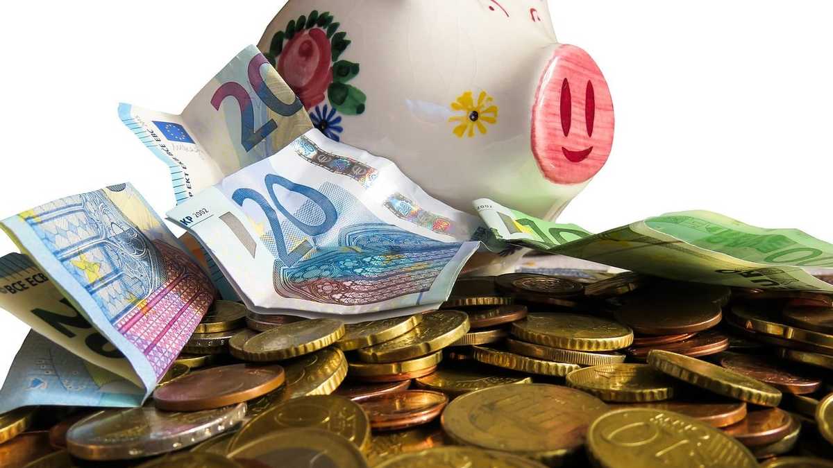 buntes Sparschein sitzt auf einem Berg Geld