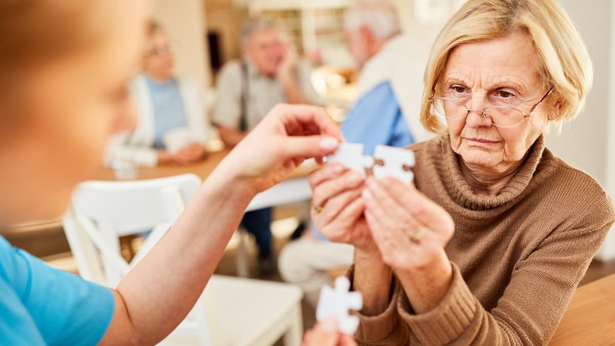 ältere Frau hält zwei Puzzleteile nebeneinander